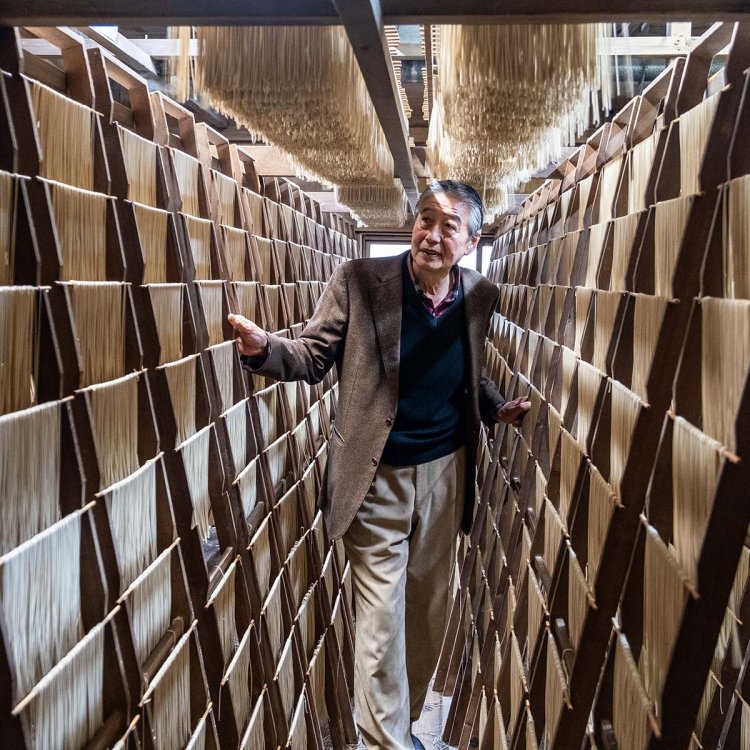 篠にかけ段々干しで乾燥中の麺と大兼宥二社長。