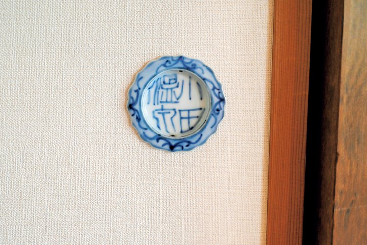 襖（ふすま）の引き手にも３代目の遊び心が。「萩の間」の引き手は「小田温泉」の文字が染め付けられた陶器製。