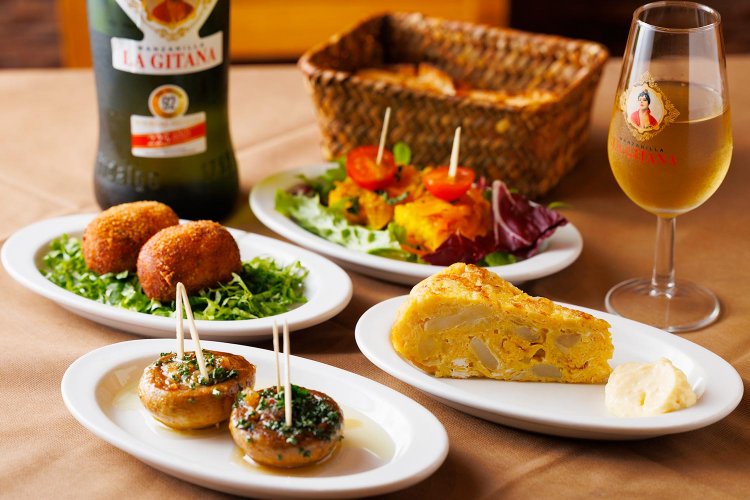 マッシュルームの鉄板焼き、アリオリソースがうまいスペイン風ポテトオムレツ各350円（ハーフ）、生ハム入りコロッケ1個300円。シェリー酒のマンサニージャ700円。