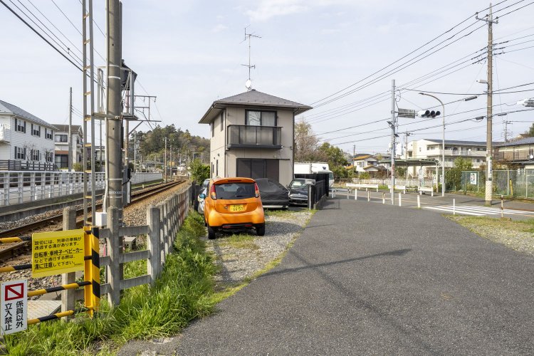 踏切脇で斜めに分岐していくアスファルトの怪しい空間。以前訪れたときはアスファルトが敷かれておらず、地面からレールが露出していた。