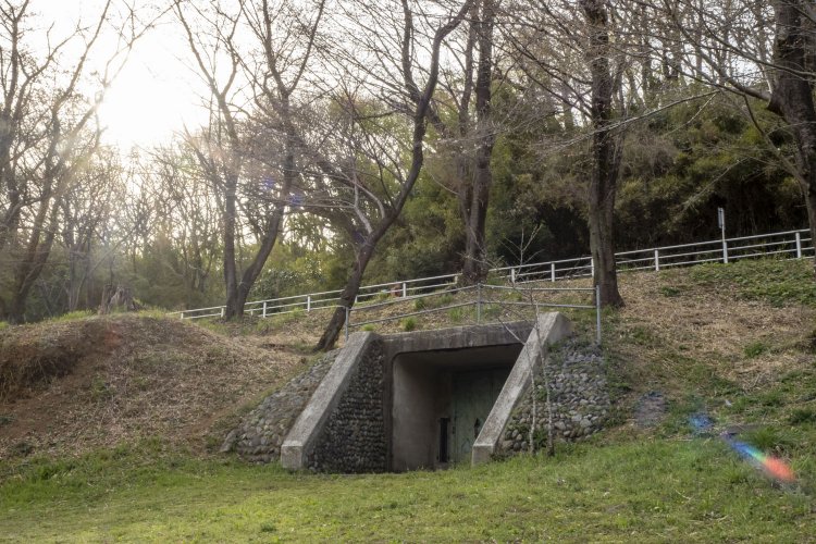 夕焼けの淡い太陽に包まれた丘陵に佇む弾薬庫。上部はサイクリングロードとなっている。