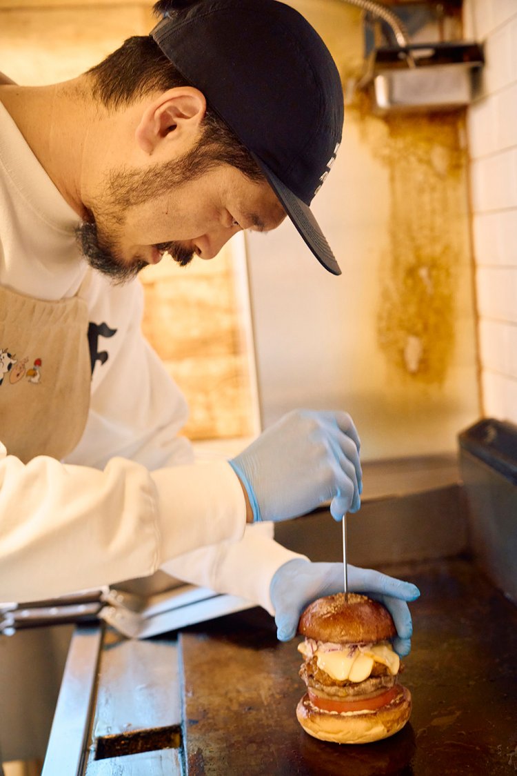 完成したバーガーに金串を刺す村上さん。