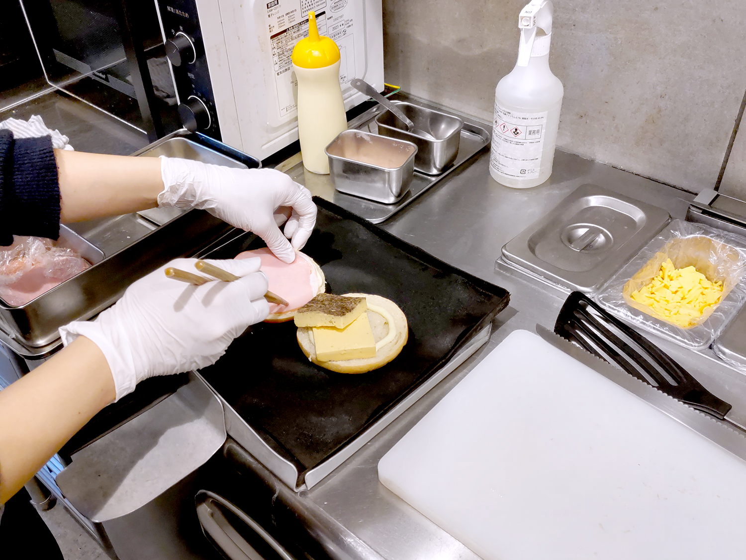 ベーグルに辛子マヨネーズを塗り、エッグフランやハムといった具材を盛り付けていく。