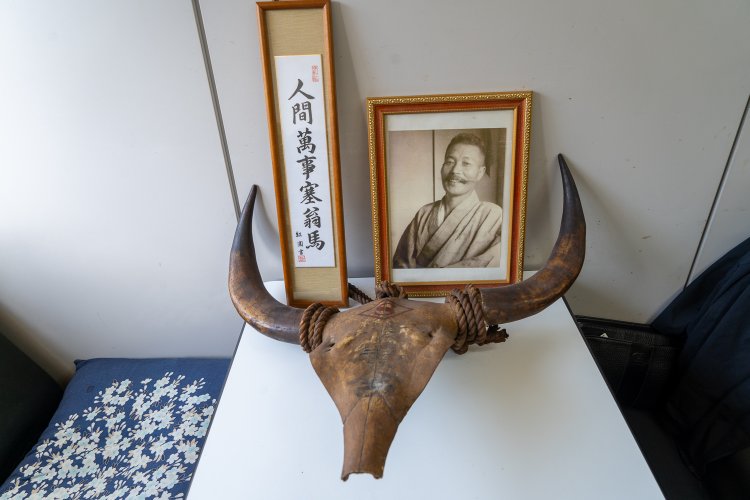 初代の写真の前にあるのは、牛乳屋さんだった頃に使われていた備品。「人間万事塞翁が馬」は家族のモットーだ。