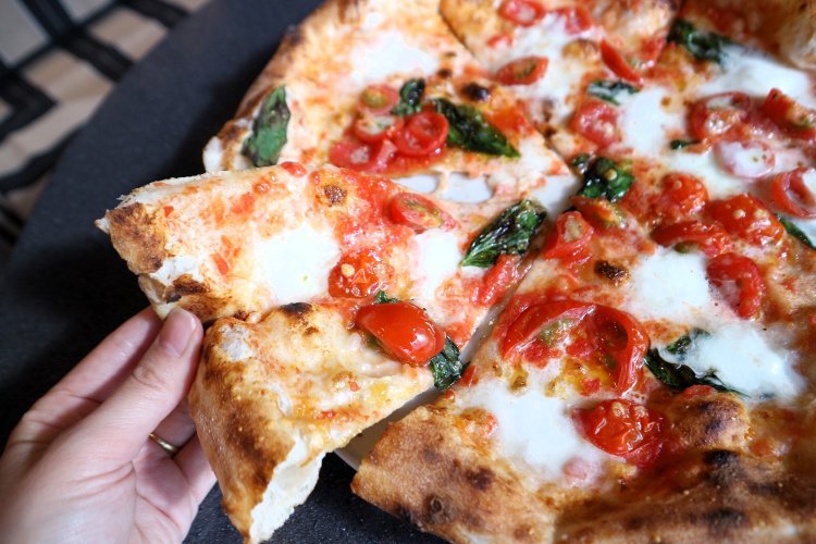 焼きたての生地には、持つとずっしりするほどチーズやトマト、バジルなど具材がのっている。