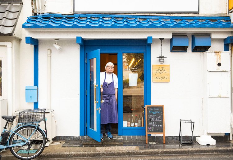 テーマカラーの青い扉と小林さん。「ワインはお好みを聞いてお出しします」。
