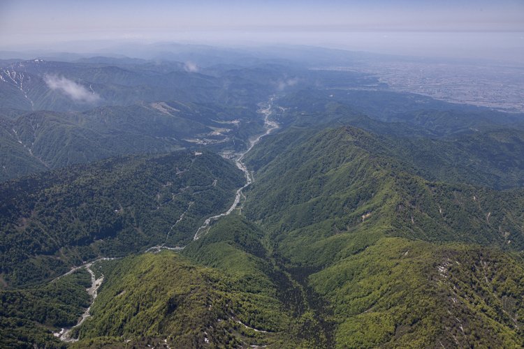 西方向を向くと、常願寺川が富山市街（右奥）に向かって流れているのが見えた。