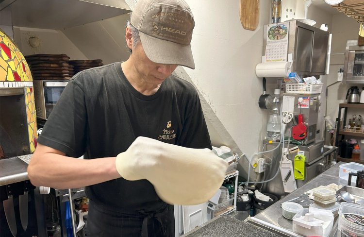 店主でオーナーの久保田茂信（くぼたしげのぶ）さんが生地を引き伸ばしているところ。