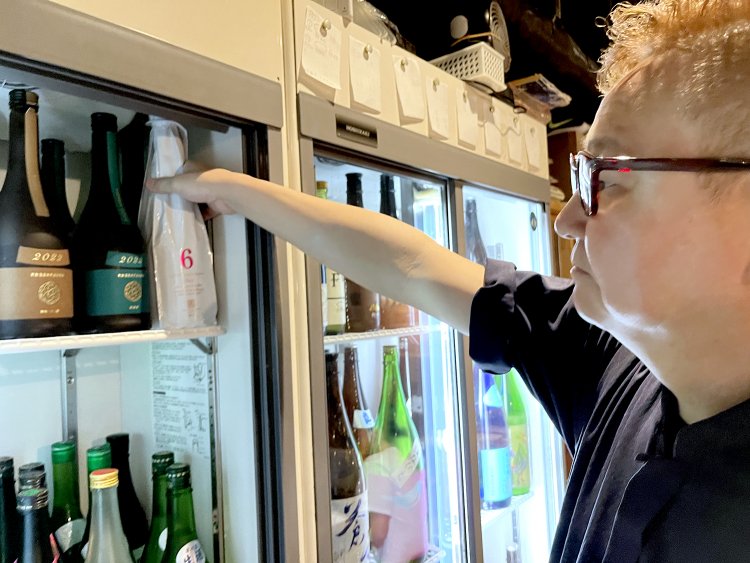 日本酒用のガラスケースにはさまざまな酒瓶がぎっしり収められている。