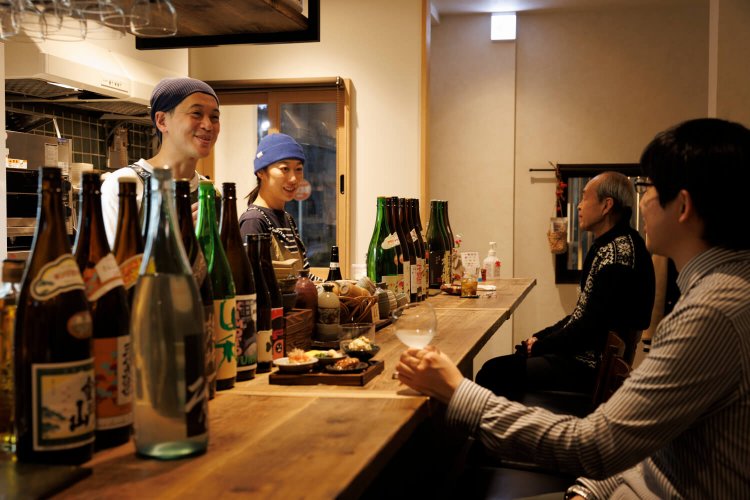 「地酒の飲み比べもぜひ」と店主の米澤さん。店主夫妻の人柄にひかれ、銭湯帰りに寄る常連も。