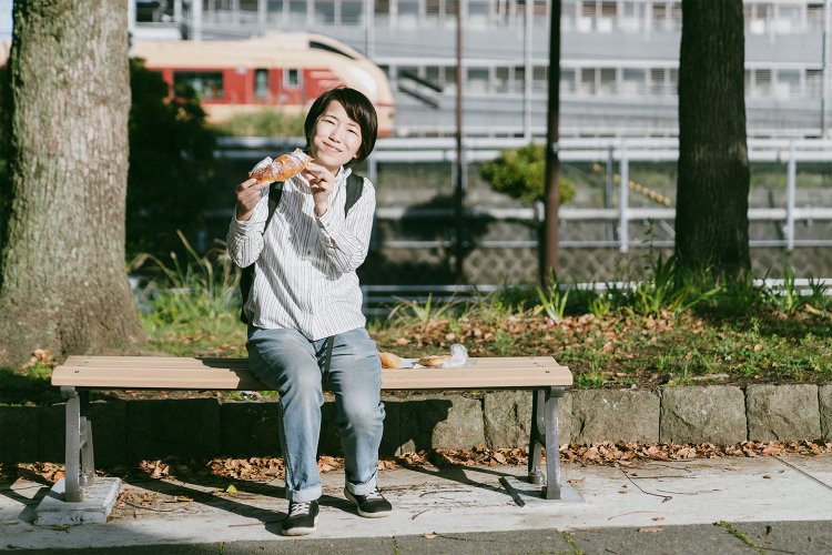 散歩とスケートで運動したあとの甘いパンは格別！　そして後ろにはまた電車が通過中。たくさん電車を見た一日だった。