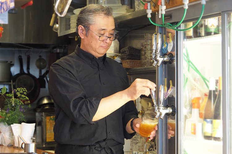 ビールを注ぐ石井さん。特注のタップを冷蔵庫の扉部分にはめこんでいるんだとか。