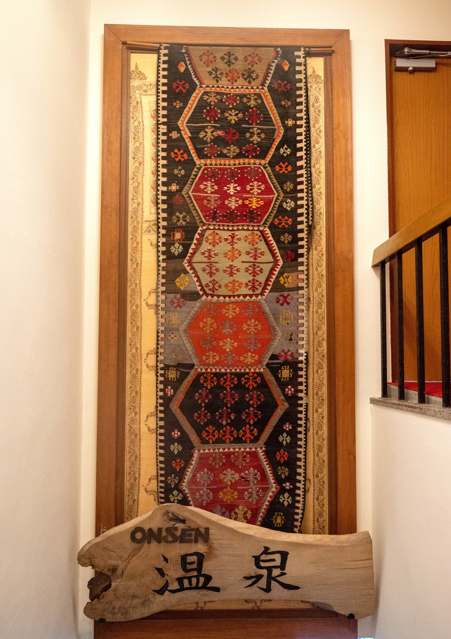 宿の随所に旅の気配が。大浴場に向かう階段に飾られたトルコのオールドキリムの絨毯（じゅうたん）。