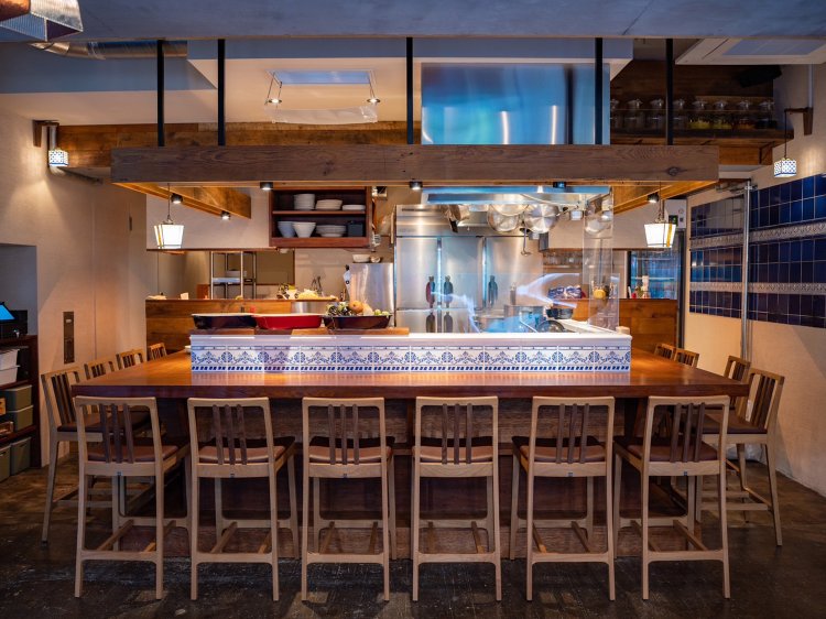 プランチャ台を備えたオープンキッチンを囲むカウンター席。店内はスペインタイルで飾られている。