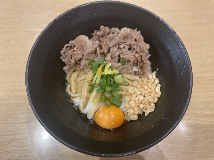 卵と肉をのせた“東京伊勢うどん”。黒い器に、白い麺と黄色い卵が美しく映える。