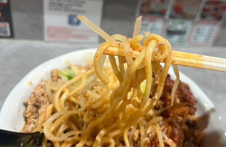 たっぷりの野菜と肉味噌、唐揚げの奥から、旨辛のスープが絡んだモチモチの麺が顔を出す。