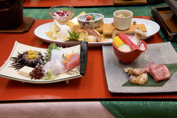 山海の幸が味わえる夕食。右は溶岩プレートで焼く鹿児島県産和牛ロースと赤鶏。奥の前菜は合鴨サラダ、流氷つぶ貝など。