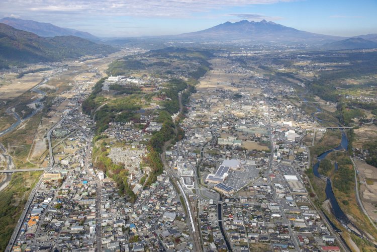 2014年11月5日空撮。手前は韮山駅。中央本線はV字状にせり上がった七里岩を登って、写真奥の八ヶ岳左手方向へ勾配を上がっていく。
