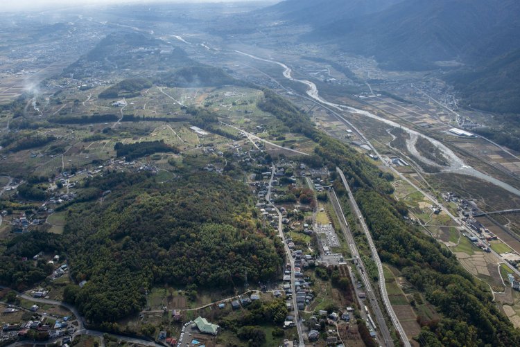 2014年11月5日空撮。七里岩の上を登っていく線路は新府駅を過ぎ穴山駅へ。この駅もスイッチバックだった。線路左手の長細い空間が旧駅の名残り。