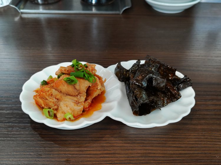 日によって変わるお通し2品。取材時は、豚すじ肉のピリ辛煮込み（左）と、パリパリ昆布（右）だった。