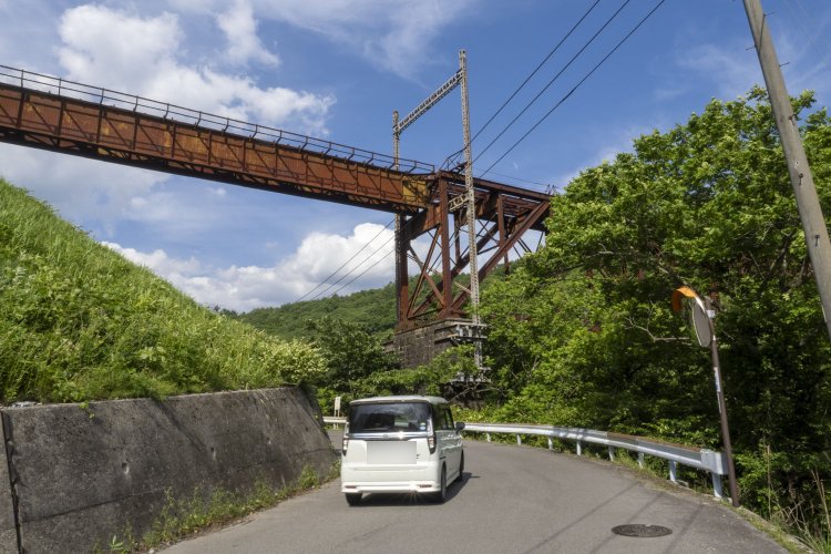 生活道路からボルチモアトラスを見る。後年に増設された架線柱が物々しい。橋梁を抱え込むように架線柱が立てられた。