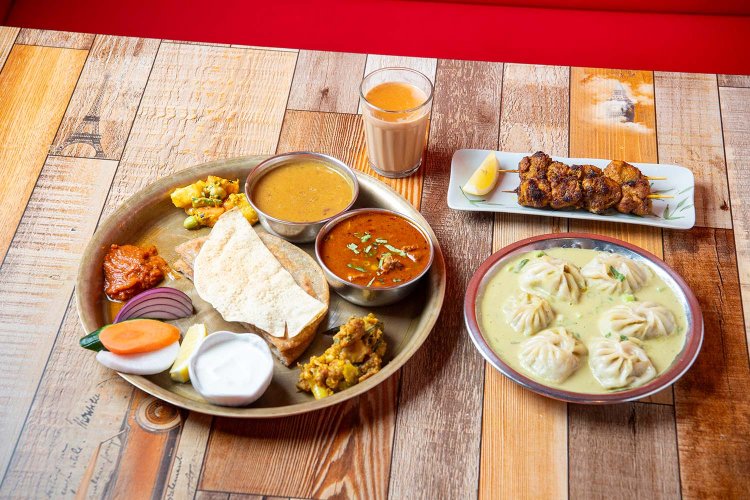 右上から時計回りに、チキンセクワ（鶏肉のスパイス串焼き）、エベレストモモ（ゴマだれスープの水餃子）、ファパルコ ロティ セット（そば粉のパンとカレーのネパール定食）、チャ（ミルクティー）。