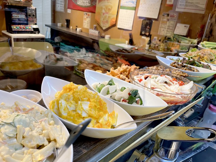 カウンターの上にはサラダ、焼き物炒め物などの大皿料理が並んでいる。色とりどりの料理が食欲をそそる。