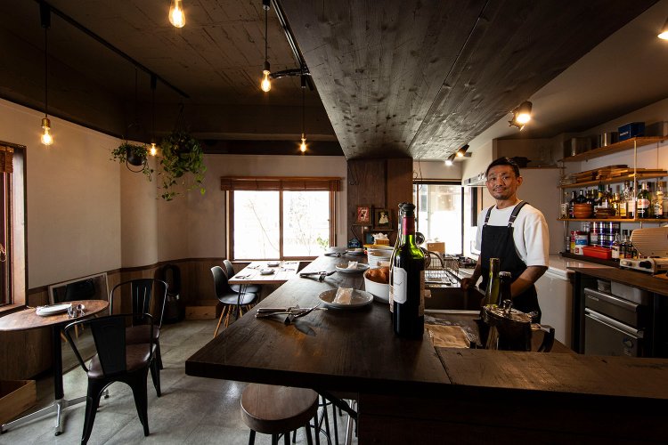 カウンター席とテーブル数席の店｡窓の向こうは熱海銀座の夜景。