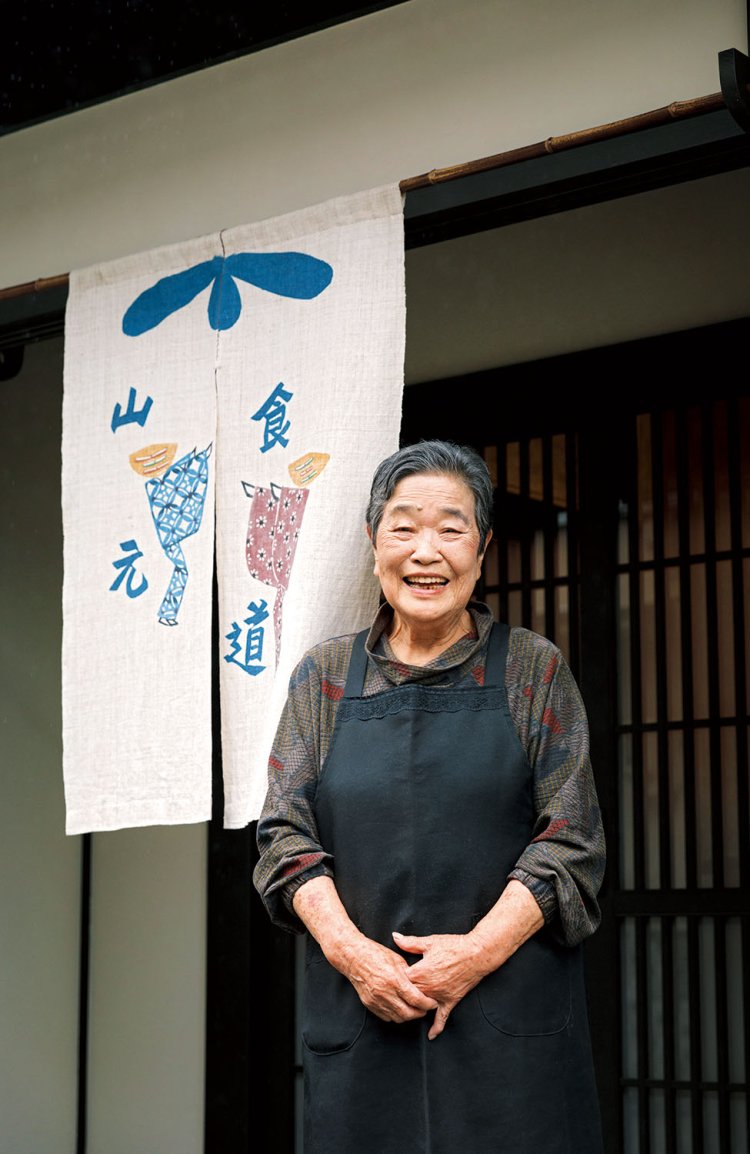 吉田さんがデザインした暖簾（のれん）と玉子さん。