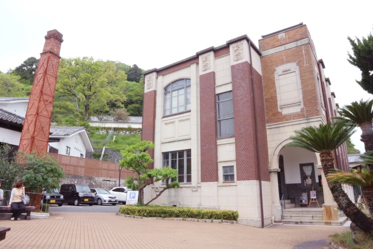 外壁に煉瓦タイルと人造石張を組み合わせた、木造洋風建築の事務所棟。