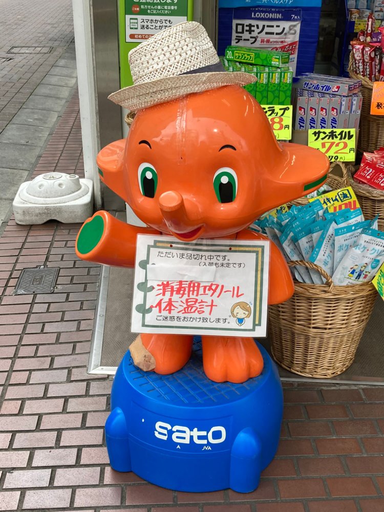 緑の目で現代風の顔立ちとなった「新サトちゃん」。帽子に全裸といういでたちではあるが、プラカードでうまいこと隠されている（聖蹟桜ヶ丘）。