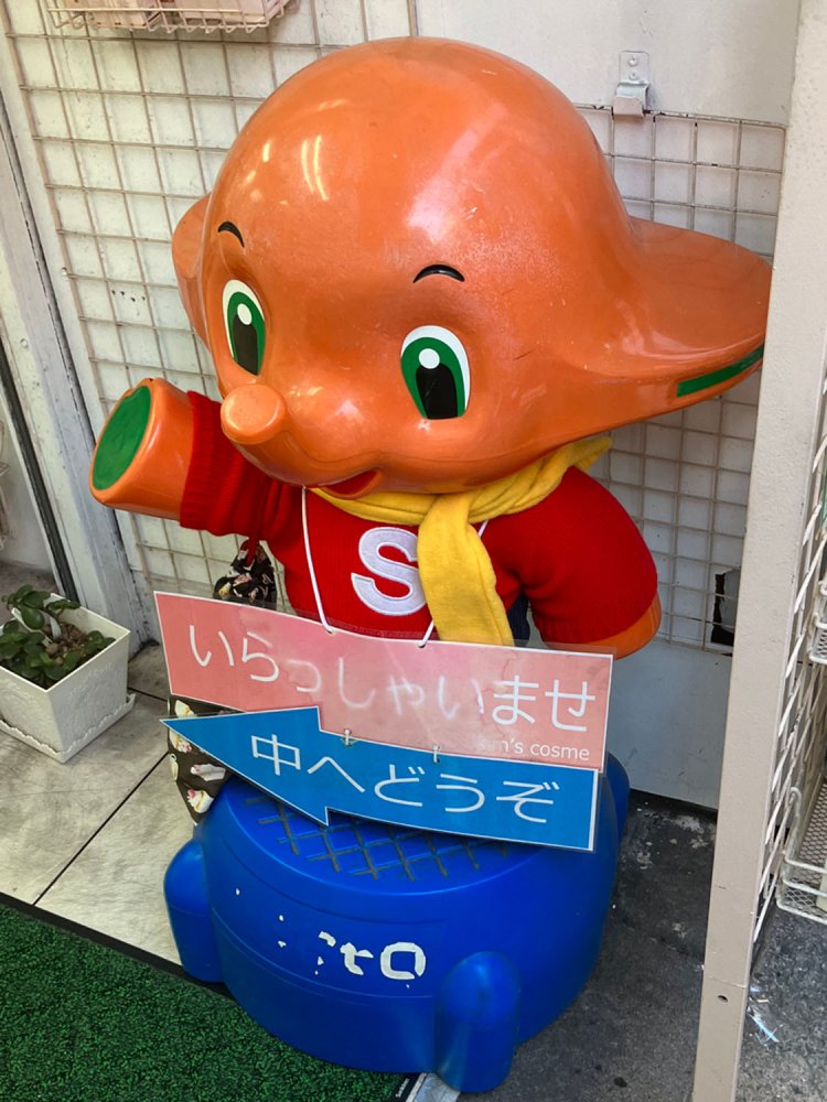 赤いトレーナーに黄色のマフラーが印象的なサトちゃん。巾着袋がオシャレのポイントか（新大久保）。