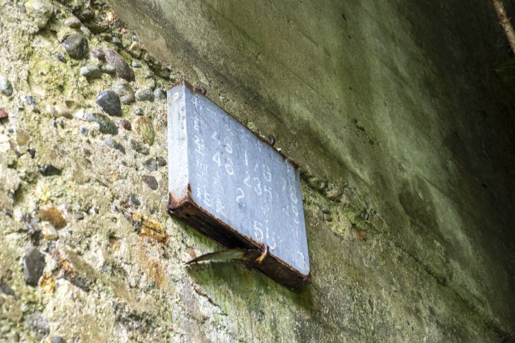 坑口の右側にさりげなくある銘板？　白文字は消えかかって見えづらい。この板も現役時からあったものだろう。