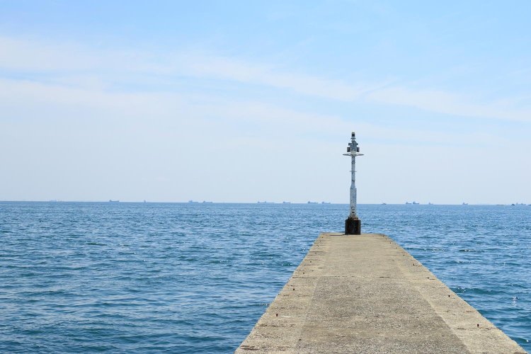 大海原に突き出す堤防の先に白灯台がポツン。夕日スポットでもあり、砂浜の豊砂の浜も近い。