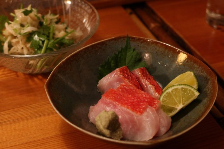 奥は「切り干し大根とパクチーの和え物」600円、手前は「金目鯛の炙り、刺身」1000円。どちらも日本酒にぴったり寄り添う酒のアテ。
