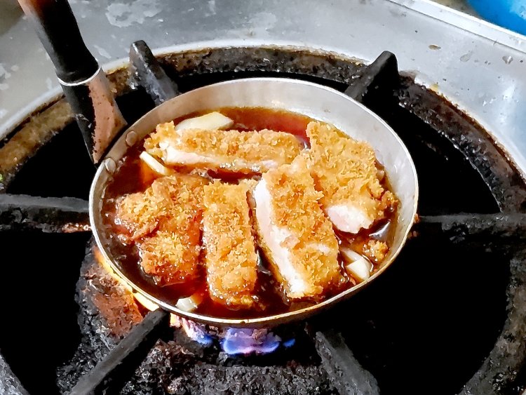 カットしたカツをタレの入った親子鍋へ投入。フタをして2分ほど煮込んでいく。