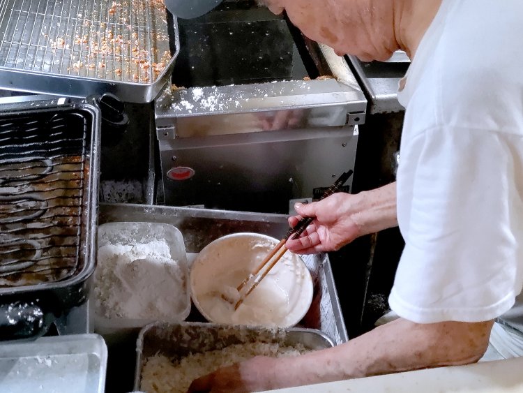 豚肉にバッター液（卵、水、小麦粉などを混ぜたもの）を絡ませてから、パン粉をまぶしていく。