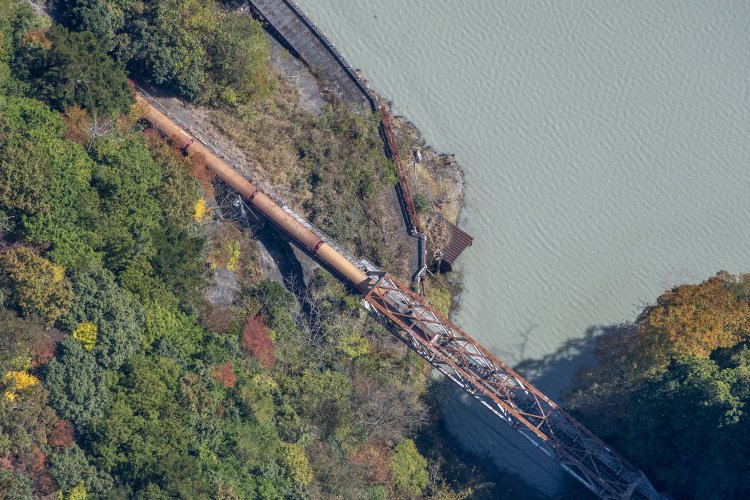 機関車のすぐ右手に屋根らしい部分があり、そこに第二犬間トンネルがあった。道路は長島ダム建設用の仮設道路。旧線は写真右手へと曲がっていった。