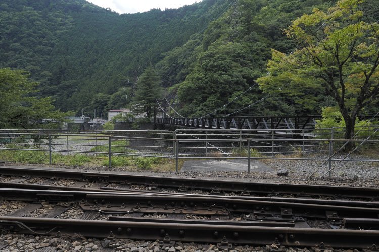 市代吊橋を横から見る。鋼製の桁である。手前の線路は井川線。アプトいちしろ駅。2024年8月16日撮影。