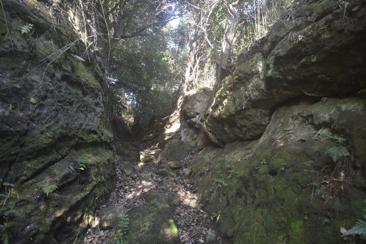 両側から削られた岩肌が迫る道。大軍を防ぐにはもってこいの造り。