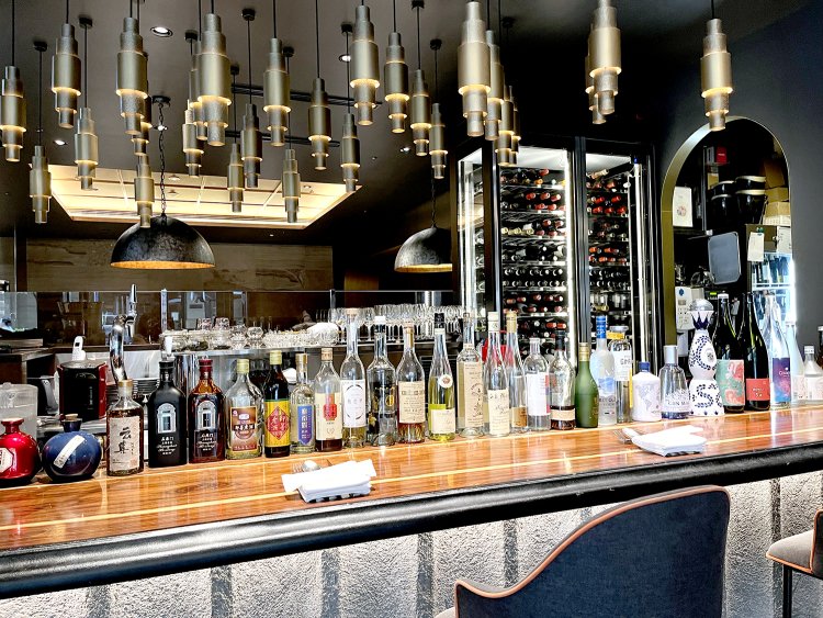 さまざまな酒瓶が並べられたカジュアルダイニングエリアのバーカウンター。