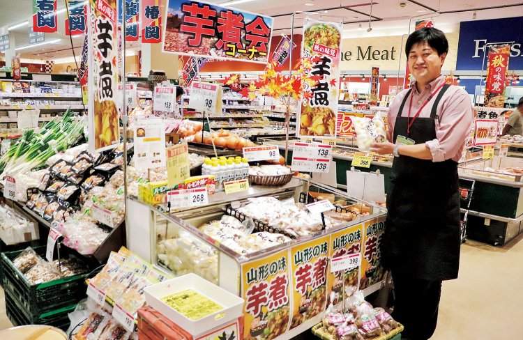 二藤部店長が持つ「洗い里芋」は、皮をむかずにすむ山形県民の必須食材。「秋の芋煮会シーズン後も、芋煮コーナーは継続します！」。