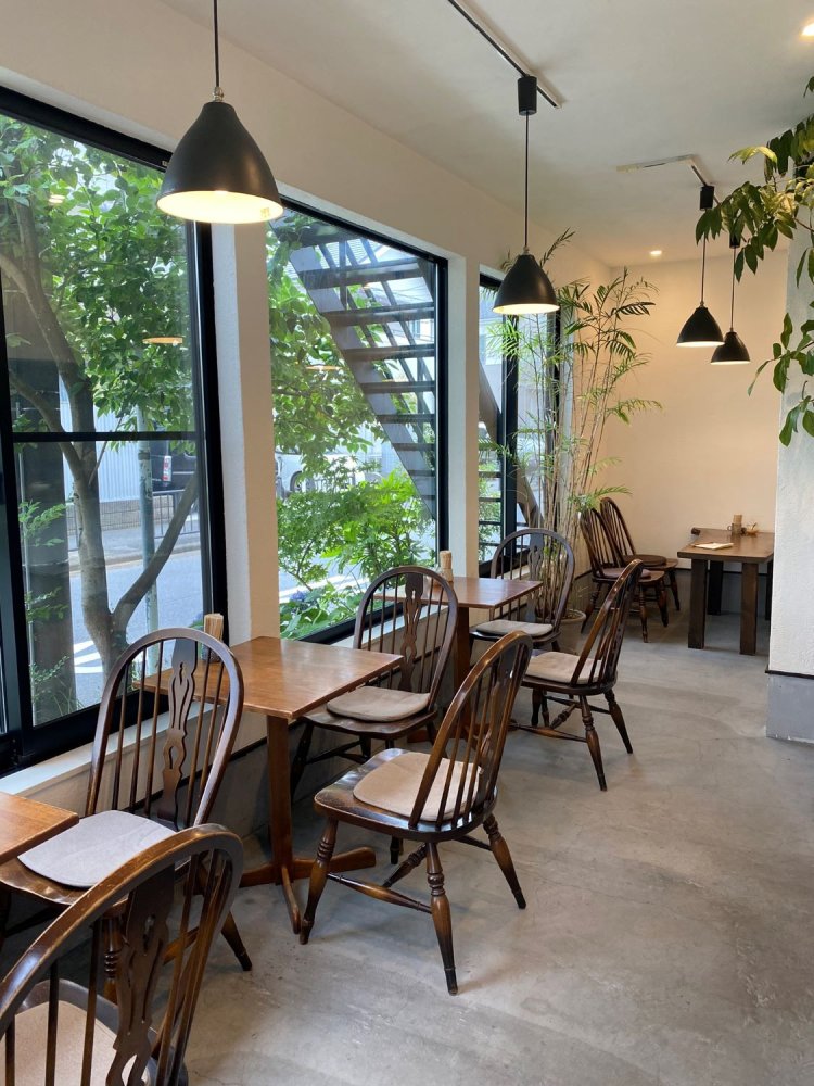 1階の喫茶スペース。植栽の緑と白い壁に木製の調度品がすがすがしい。