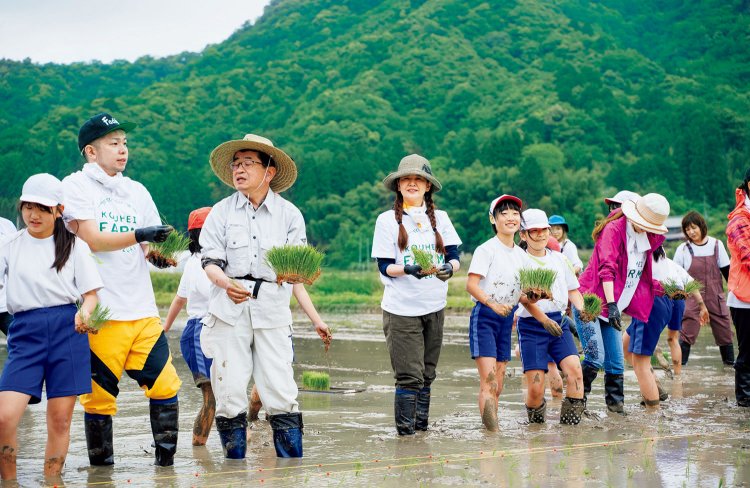 舞鶴で、地元の小学生たちと一緒に田植えをする南野さん。田んぼにはにぎやかな声が響く。