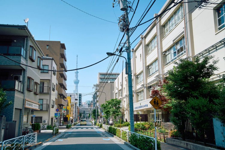 二人の通っていた中学校は、下町の空気が漂う住吉銀座商店街にある。通りの向こうには東京スカイツリーが。