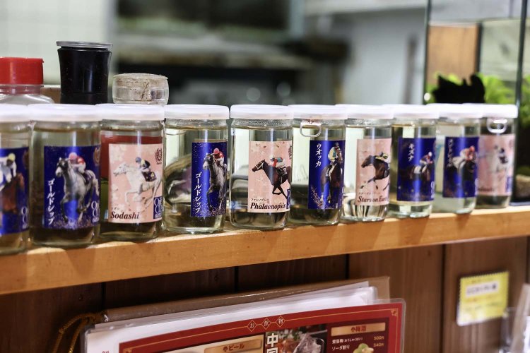 ウォッカにゴールドシップ、ファレノプシスとすべて馬の名前。その下には、競馬馬の名前が入ったカップ酒の空き瓶がずらり。 「ストリップも競馬も好きなんですよ」と福永さん。