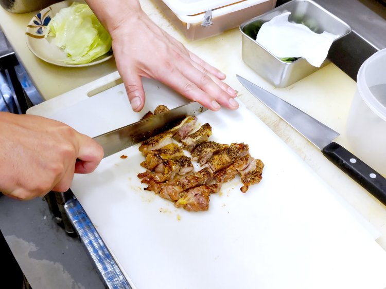 焼き上がったら包丁でひと口大にカット。力の入れ具合から親鶏ならではの硬めの肉質が伝わってくる。