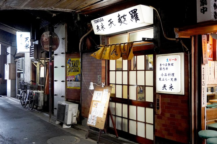 昼間でもほの暗いガード下に、飲食店の看板の灯りが点る。