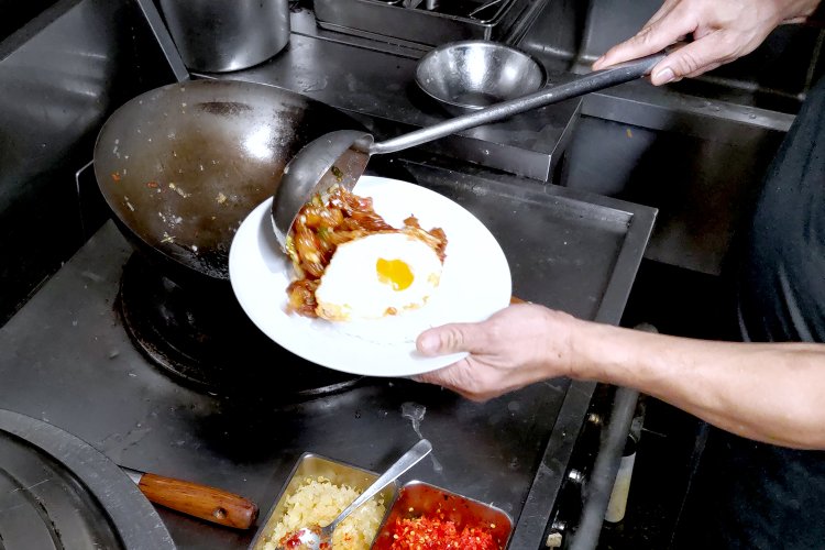 目玉焼きをのせたジャスミンライスに、炒めた豚肉を盛り付ける。あとはパクチーやキュウリを添えるだけ。