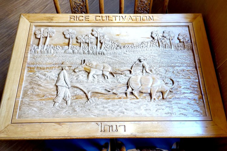 木彫りのテーブルには、さまざまなタイの風景が描かれており、サイズや形状によって絵柄が異なる。